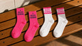 Pink and white Creative Champions socks laid out on a wooden bench
