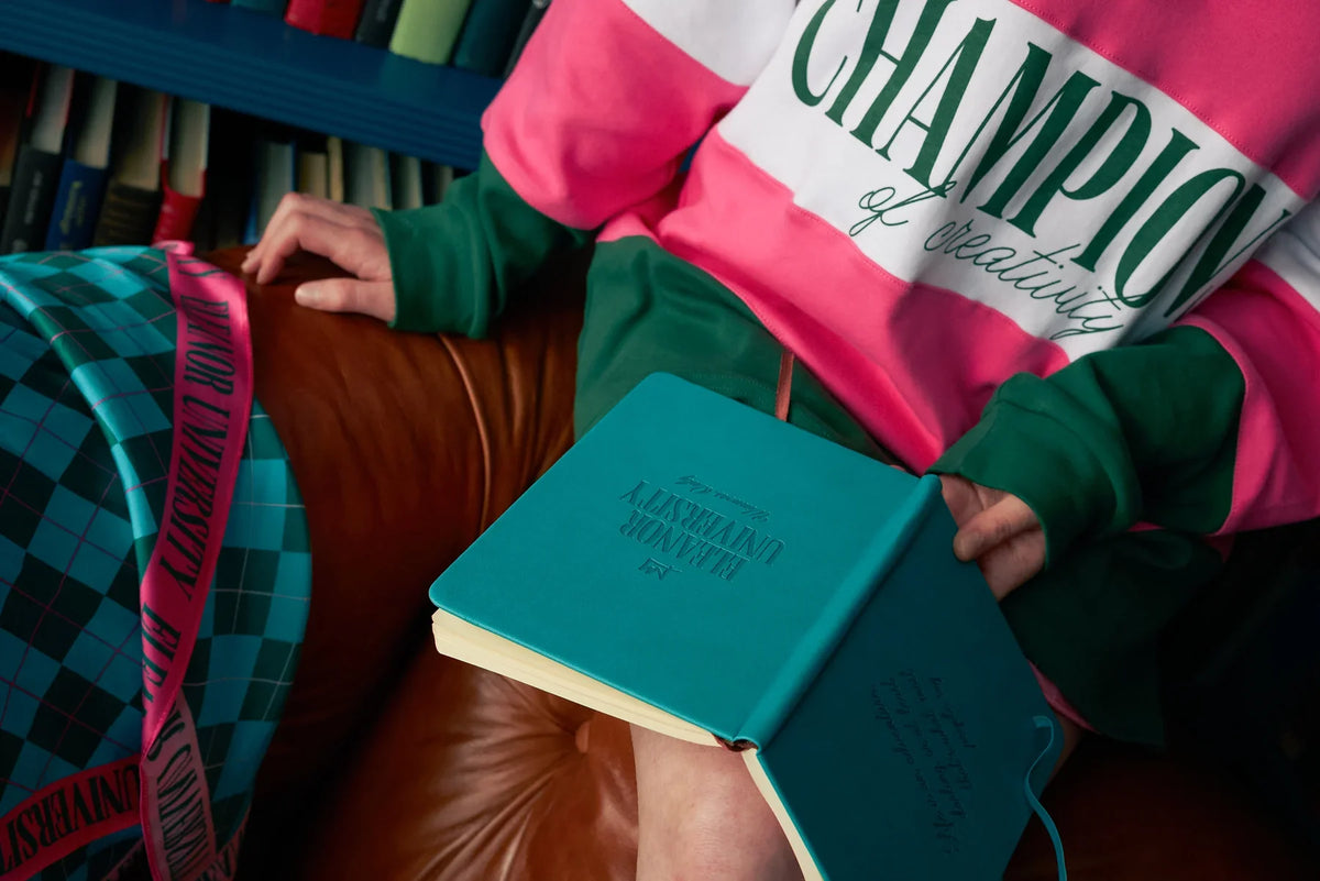 Face-free detail of the pink, white and forest-green Champions rugby shirt, worn with the University scarf and notebooks