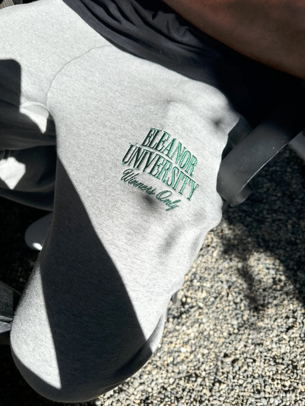 Detail of green Eleanor University Winners Only embroidery on grey sweatpants